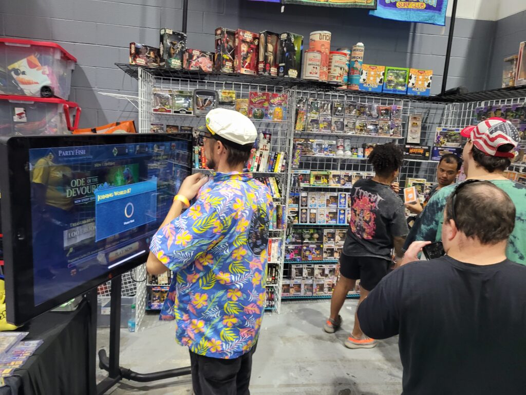 Person using a large Padzilla touchscreen at a toy and collectibles trade show booth.