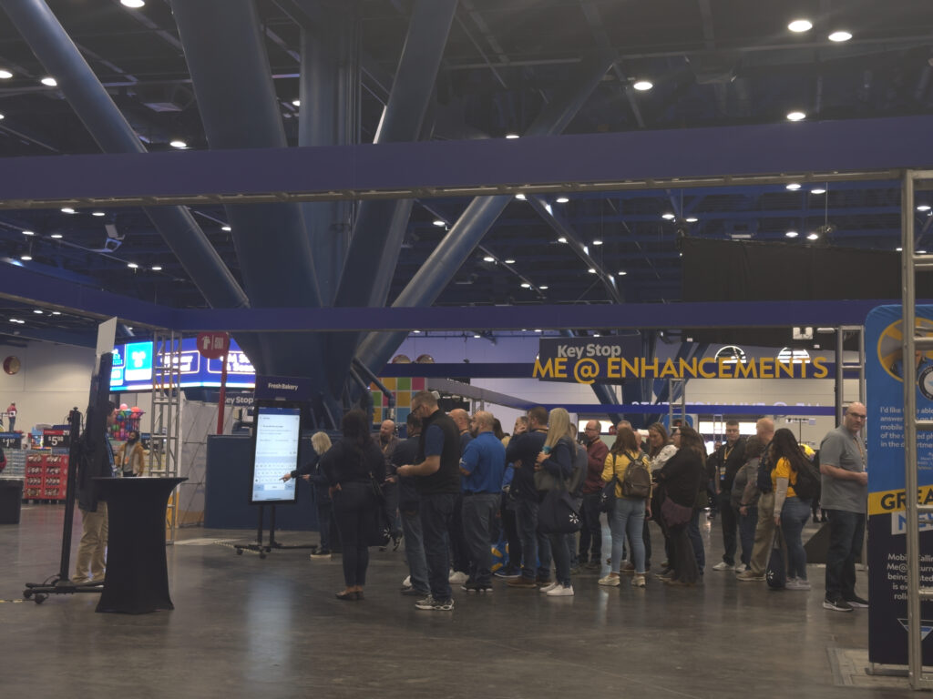 Trade show attendees line up at interactive touchscreen kiosk